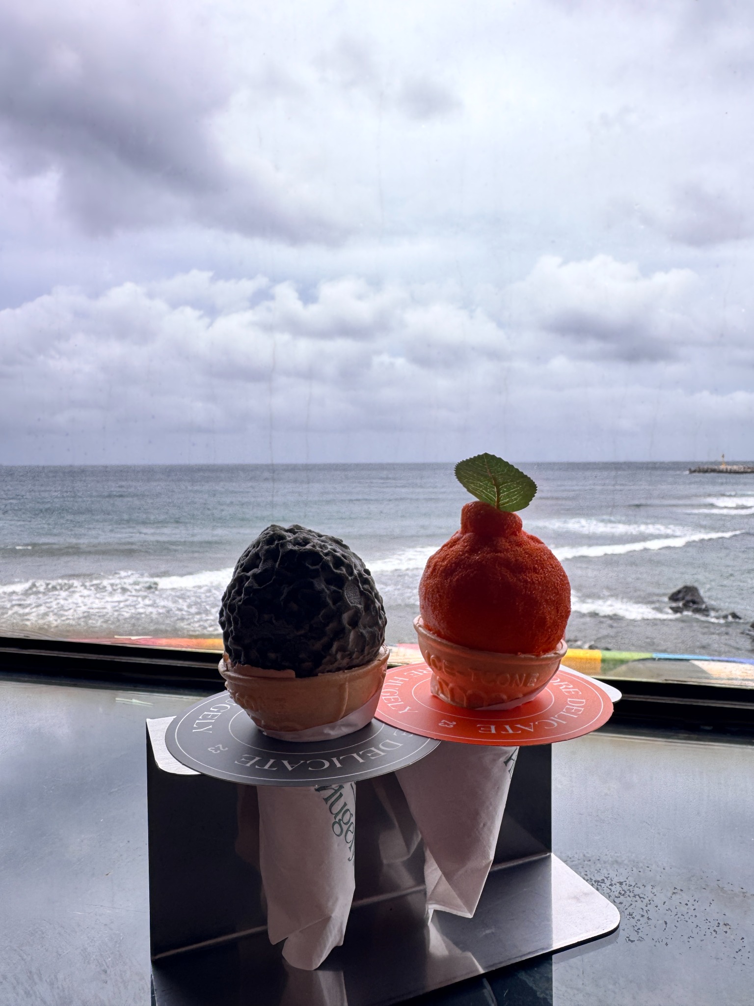 Duas sobremesas de Jeju diante de uma janela com vista para o oceano