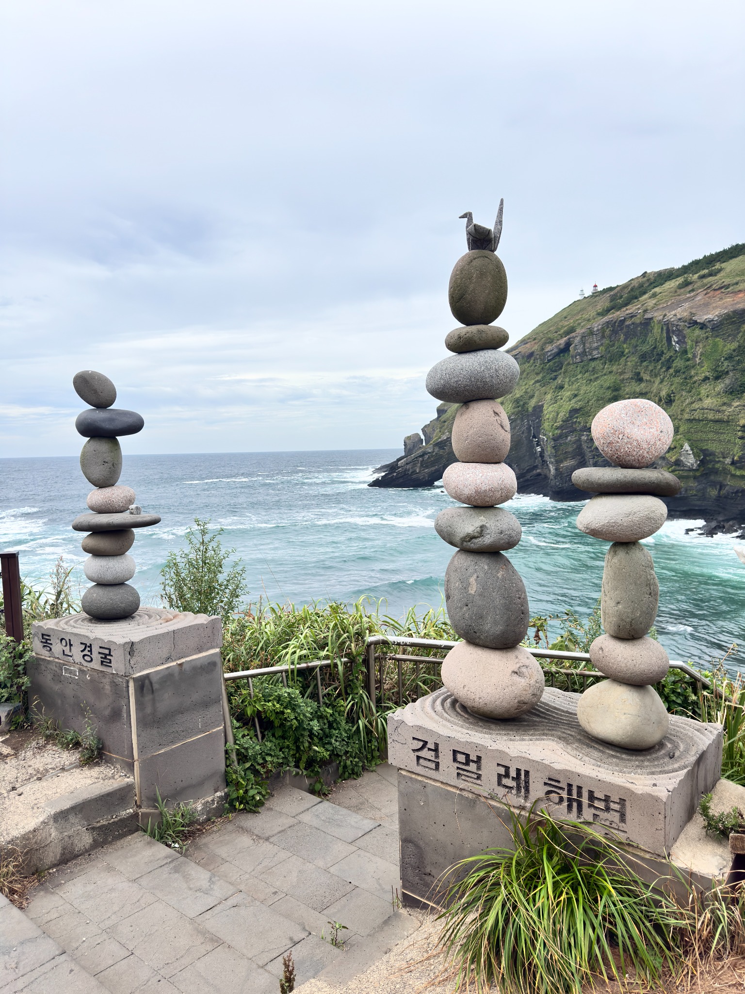 Pedras empilhadas diante do oceano e de uma falésia em Jeju